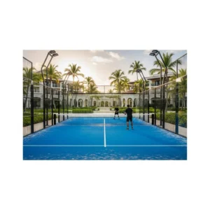 Un campo da padel moderno e ben curato all'interno del lussuoso Puntacana Resort, con palme e vegetazione tropicale sullo sfondo e giocatori in silhouette.