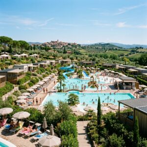 Complesso di piscine di lusso con scivoli e bungalow moderni in un campeggio che sembra un resort italiano, con figure di famiglie in lontananza.