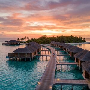 Resort di lusso con ville overwater e pontili in legno al tramonto alle Maldive. (Immagine generata con IA)