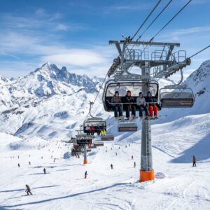 Un moderno impianto di risalita a otto posti in una stazione sciistica di lusso con piste innevate e sciatori in lontananza.