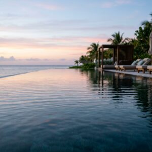 Scatto a filo d'acqua di una lussuosa piscina di resort all'alba, con riflessi rosa e blu del cielo mattutino sulla superficie calma. Si intravedono eleganti arredi a bordo piscina sullo sfondo. (Immagine generata con IA)